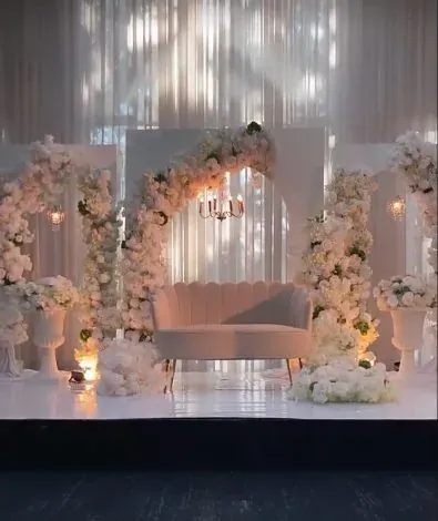 Arche de roses blanches et sofa sur scène, décor floral illuminé