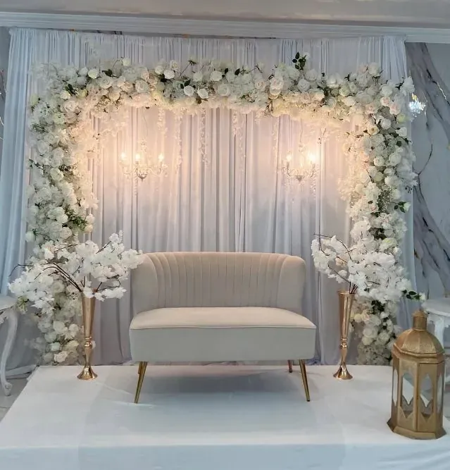 Arche florale blanche illuminée, sofa beige et lanternes dorées
