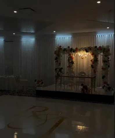 Arche florale et piste de danse monogrammée dans une salle tamisée