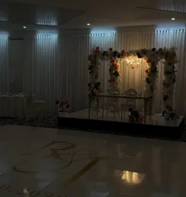 Arche florale illuminée sur scène et piste de danse monogrammée, ambiance tamisée