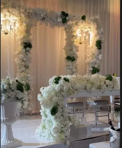 Arches florales blanches et cascade de roses sur la scène des mariés