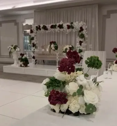 Bouquet bordeaux et blanc au pied d’une arche florale