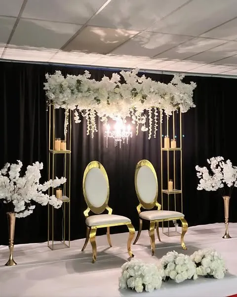 Canopée florale blanche, lustre et chaises dorées sur fond noir