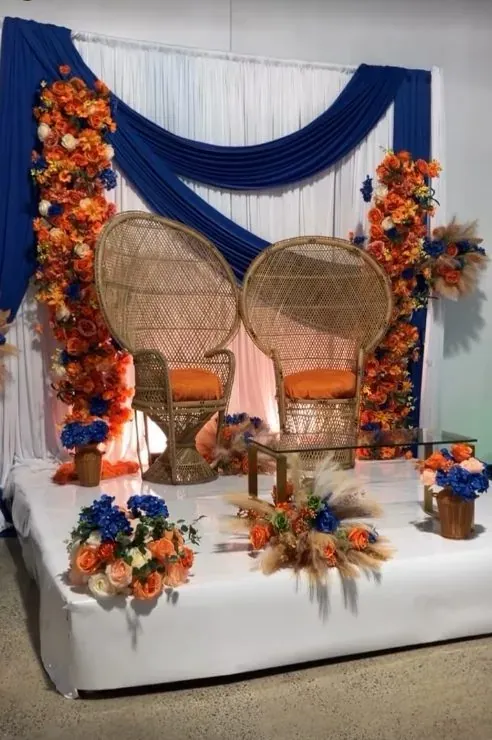 Décoration de cérémonie traditionnelle avec draperie bleue, fleurs orange et fauteuils en rotin