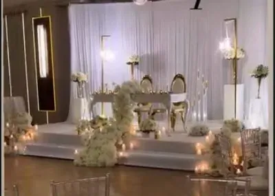 Draperie blanche, cadres dorés lumineux et table d’honneur fleurie sur grande scène