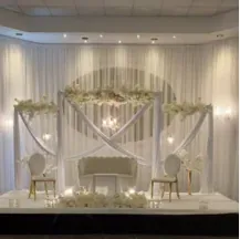 Drapés croisés, guirlandes florales et sofa entre deux chaises dorées sur scène