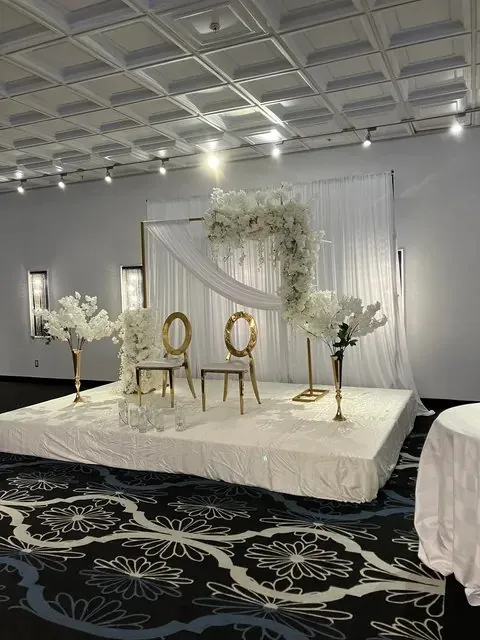 Estrade blanche avec drapé, cadre floral et chaises dorées — vue de côté