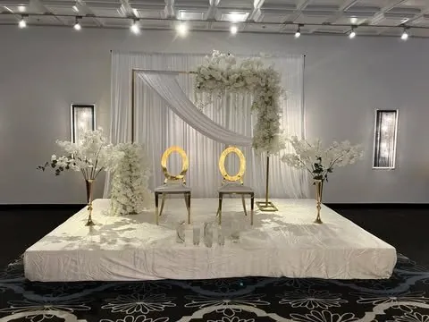 Estrade blanche, drapé en diagonale, cadre floral et chaises dorées
