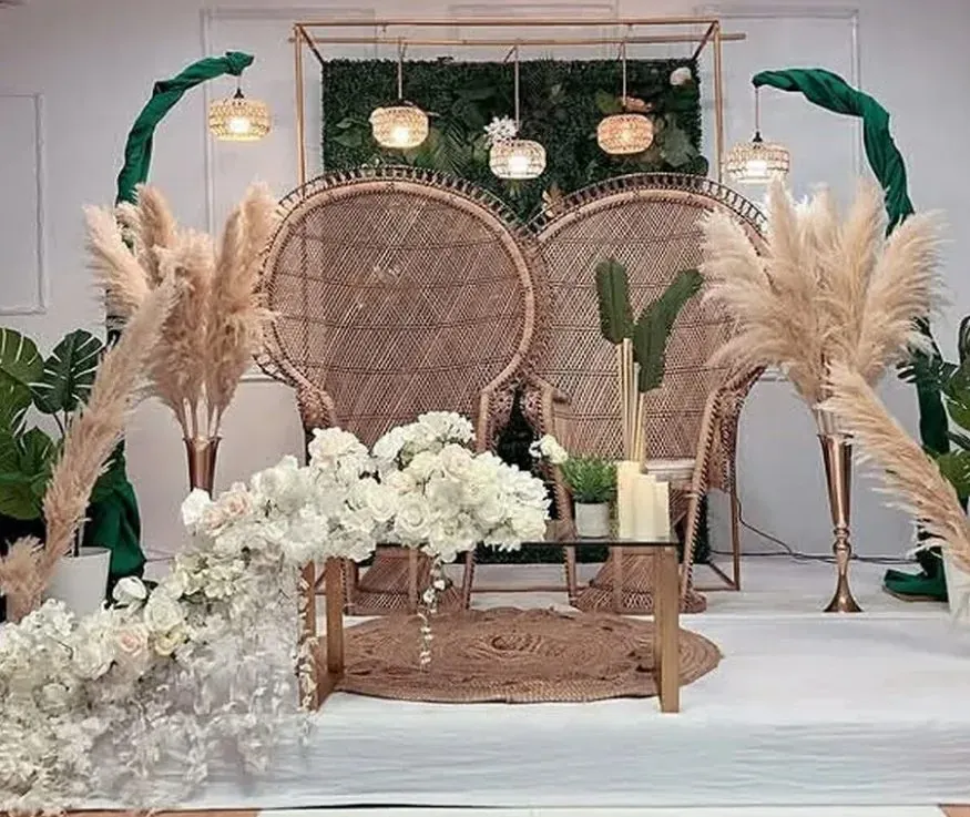 Fauteuils en rotin, herbes de la pampa et fleurs blanches sur fond de verdure