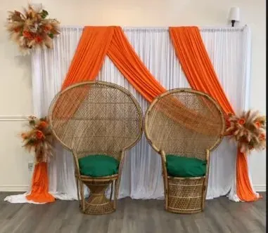 Fauteuils paon en rotin, draperie orange et blanche et bouquets d’automne