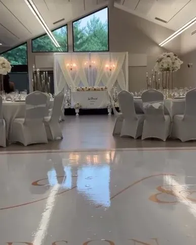 Salle de réception avec scène drapée de blanc et tables habillées