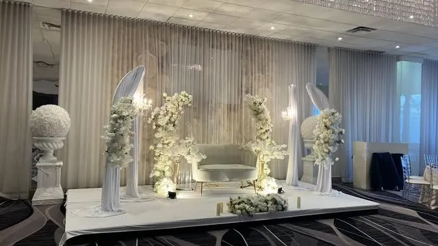 Scène blanche avec arches drapées, colonnes et sofa — vue d’ensemble