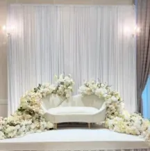 Sofa blanc entouré de roses blanches devant une draperie