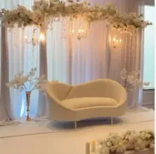 Sofa courbé ivoire sous une guirlande florale blanche et des appliques
