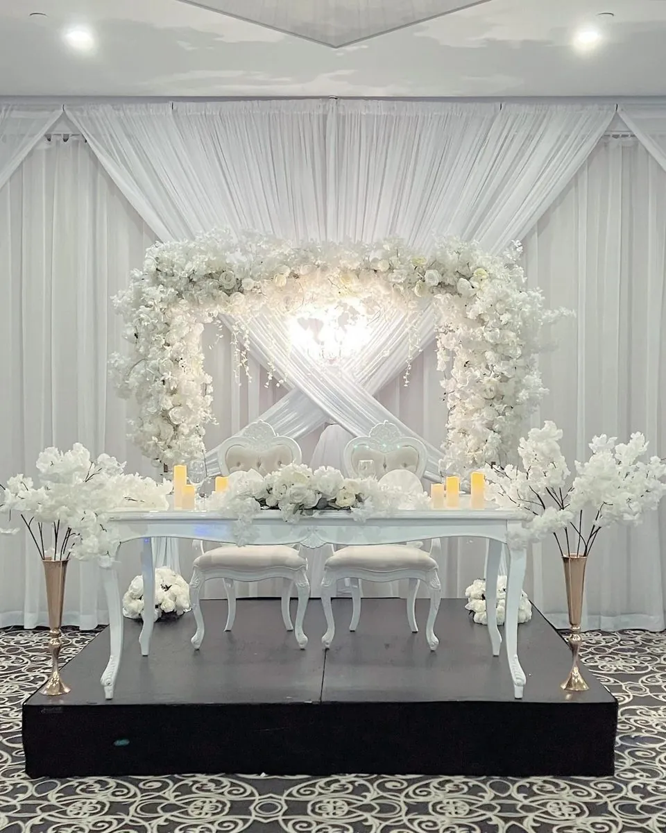 Table d’honneur blanche, drapé croisé et cadre floral blanc