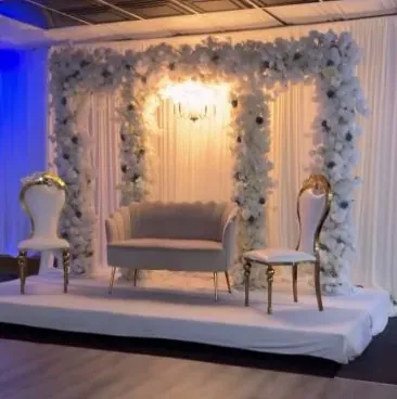 Trois arches de fleurs blanches, sofa et chaises dorées sous éclairage bleu