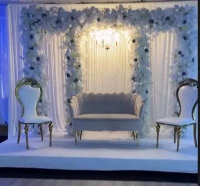 Trois arches florales, sofa gris et chaises dorées sur estrade blanche
